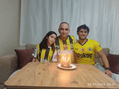 three people posing for a picture with one wearing a yellow shirt that says otokoc