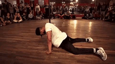 a man in a white shirt is doing a handstand on a wooden floor