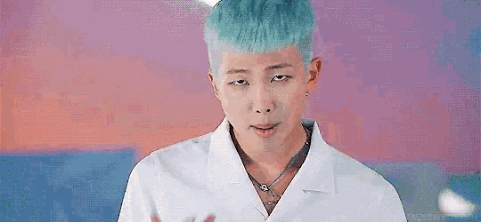 a close up of a person with blue hair wearing a white shirt and a necklace .