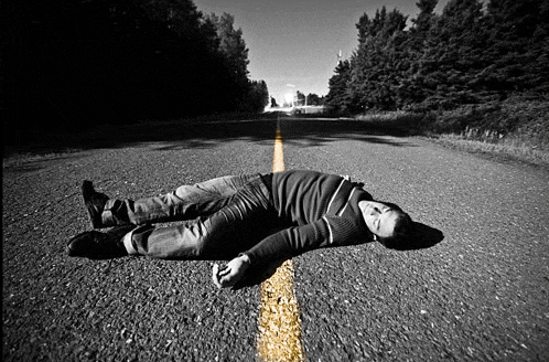 a man laying on the road with a yellow line