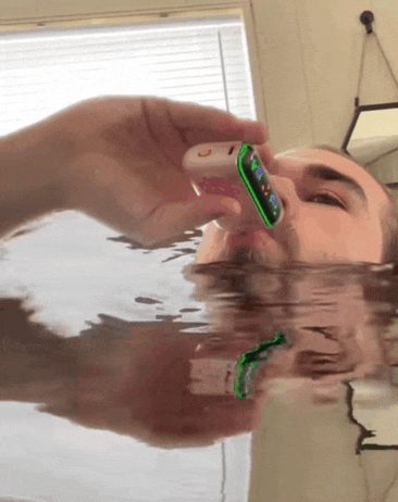 a man is holding a cell phone in his mouth while swimming in a bathtub