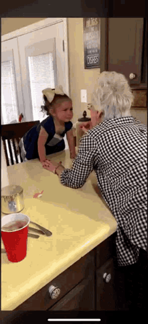 a little girl is sitting at a table with an older woman in front of a sign that says hugs