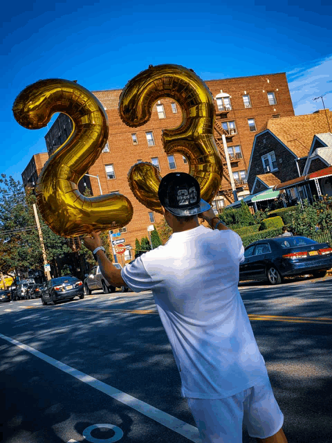 a man in a white shirt is holding up balloons that say 23