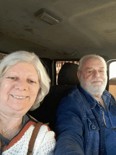 a man and a woman in a car smiling for the camera