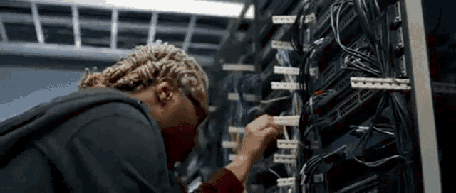a man wearing glasses is working on a server in a server room .