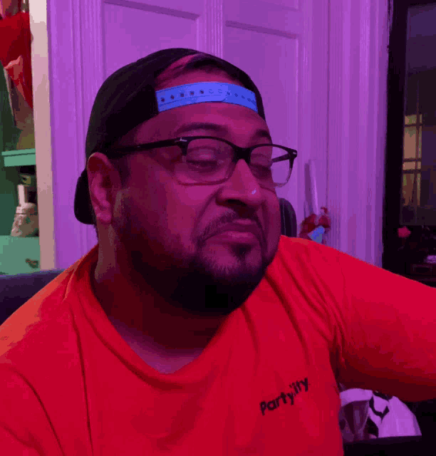 a man wearing glasses and a red shirt that says partyally
