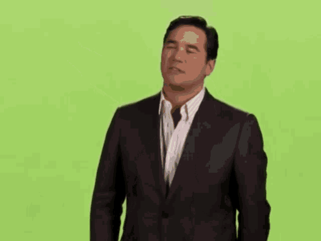 a man in a suit and white striped shirt is standing on a green screen