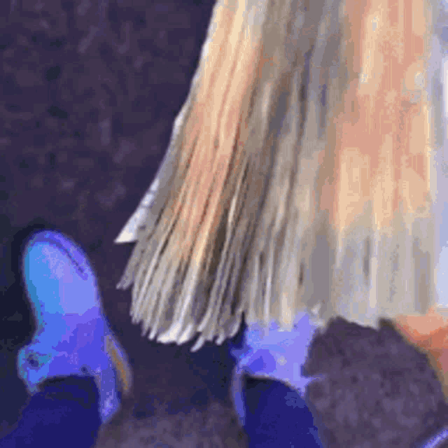 a close up of a person 's feet wearing blue boots and a long blonde haired doll .
