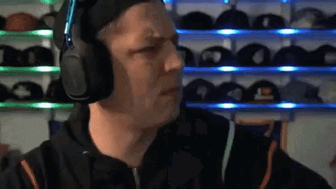 a man wearing headphones in front of a shelf of hats