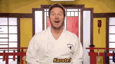 a man in a karate uniform is standing in front of a yellow wall in a room .