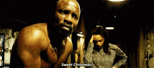 a man without a shirt is standing next to a woman in a dark room and says sweet christmas .