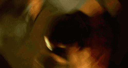 a person is holding a batman logo in their hand in the dark .