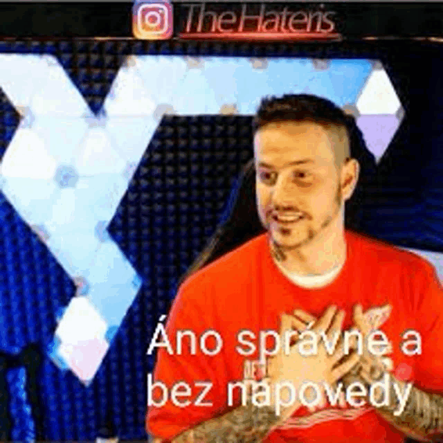 a man in a red shirt is sitting in front of a screen with a foreign language on it .