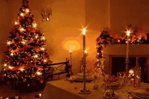 a christmas tree is lit up in front of a fireplace