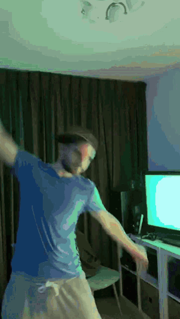 a man in a blue shirt is dancing in front of a green screen