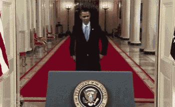 a man in a suit and tie is standing in front of a podium with the seal of the president of the united states .