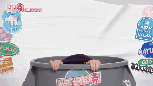 a person is sticking their head out of a recycling bin surrounded by stickers including one that says keep the ocean clean
