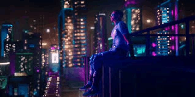 a man is sitting on a ledge overlooking a city at night .