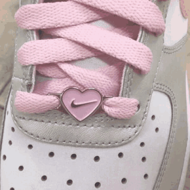 a close up of a pair of nike shoes with pink laces and a pink heart shaped nike logo .