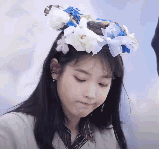 a girl with a flower crown on her head looks down