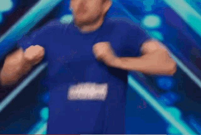 a man in a blue shirt and black pants is dancing on a stage