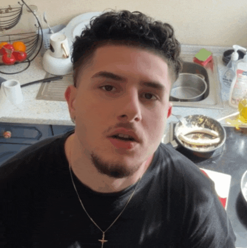 a man wearing a black shirt and a cross necklace looks at the camera