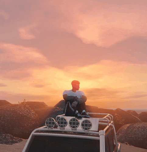 a man sits on the roof of a vehicle watching the sunset