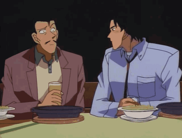 two men sitting at a table with a bowl of soup