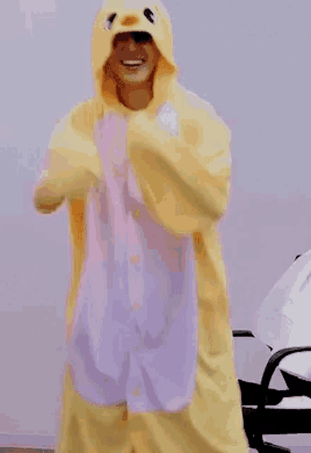 a person is wearing a yellow and purple duck costume and dancing .