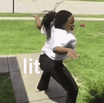 a woman is dancing on a sidewalk in front of a grassy field with the word lit written on the sidewalk .