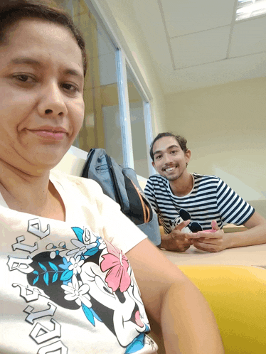 a woman wearing a minnie mouse t-shirt sits next to a man