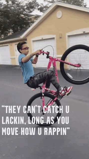 a young boy is doing a trick on a pink bike with a quote behind him