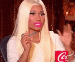 a woman with blonde hair and pink lips is holding a coca cola cup .