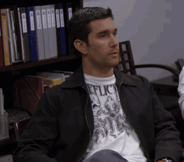 a man wearing a black jacket and a white shirt that says reflect