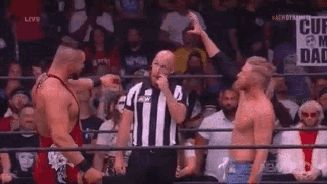 two men in a wrestling ring with a sign that says curse me daddy on it