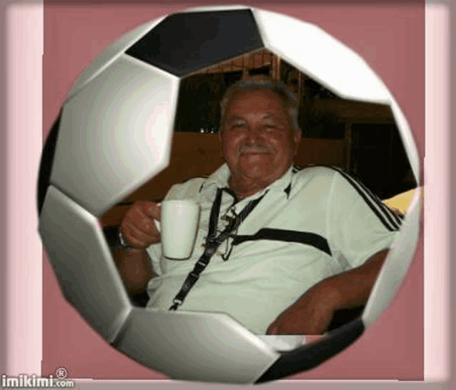 a man is sitting inside of a soccer ball holding a cup