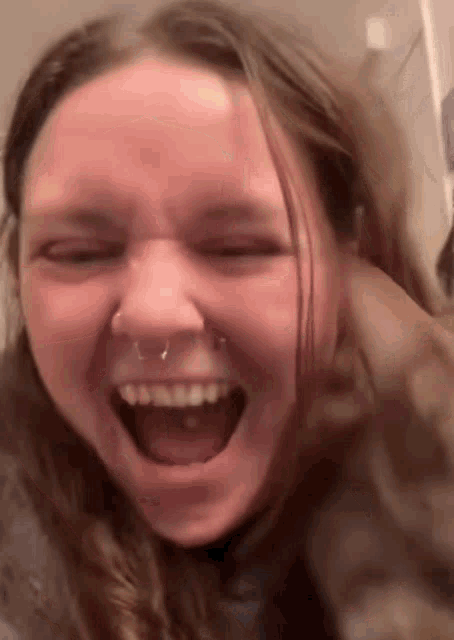 a woman with a nose ring is making a funny face with her mouth open