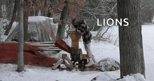 a man is using a wood chipper in the snow with the word lions above him .