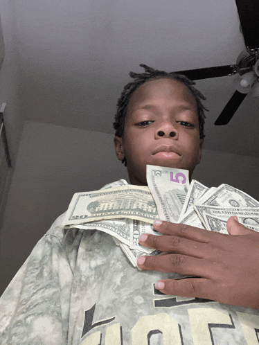 a young boy holds a stack of 5 dollar bills