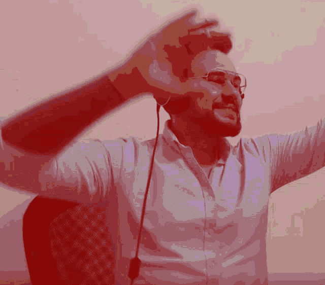 a man wearing glasses and headphones holds his hands up in the air