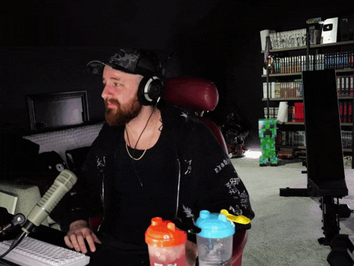a man with a beard is sitting in front of a microphone and a shaker that says ' sd '