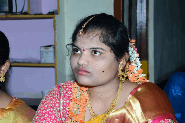 a woman with flowers in her hair and earrings looks at the camera