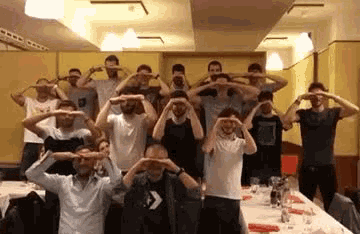 a group of men are standing in front of a table with their hands on their faces
