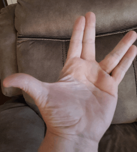 a person 's hand is extended in front of a grey leather chair