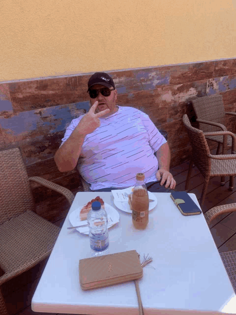 a man sitting at a table with a plate of food and a bottle of water