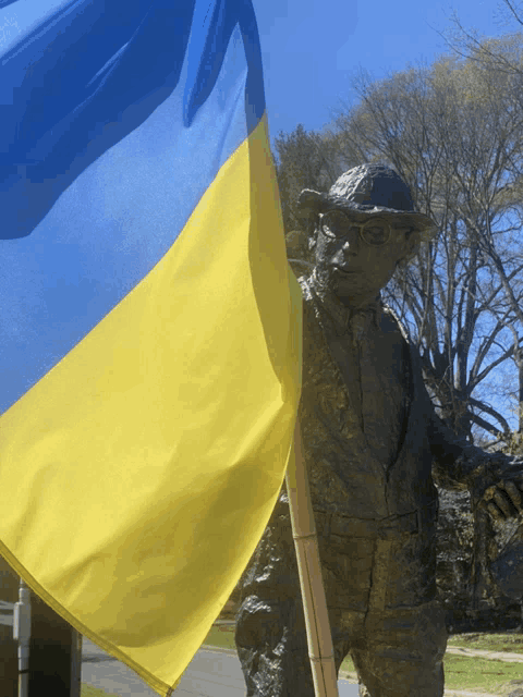 a statue of a man in a hat holding a yellow and blue flag