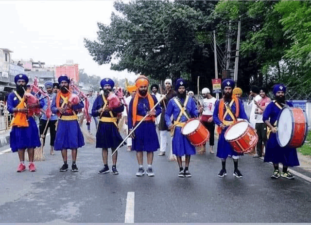 a group of men are marching down a street playing drums and playing instruments