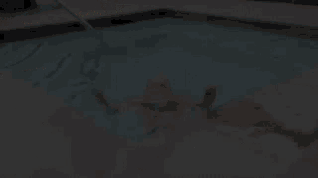 a woman in an orange bikini is swimming in a swimming pool