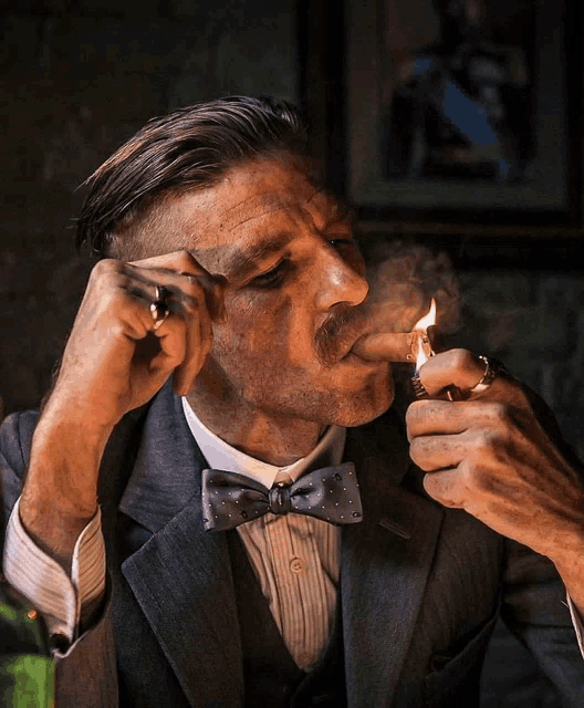 a man in a suit lighting a cigar with a lighter