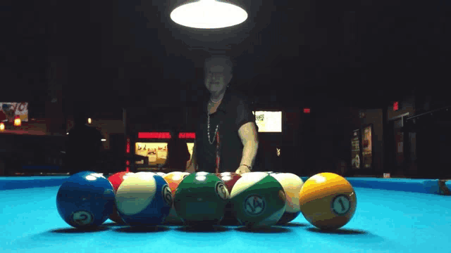 pool balls on a table with a man standing in the background